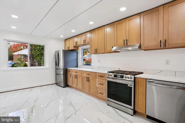 a kitchen with stainless steel appliances granite countertop a refrigerator a stove top oven a sink and dishwasher