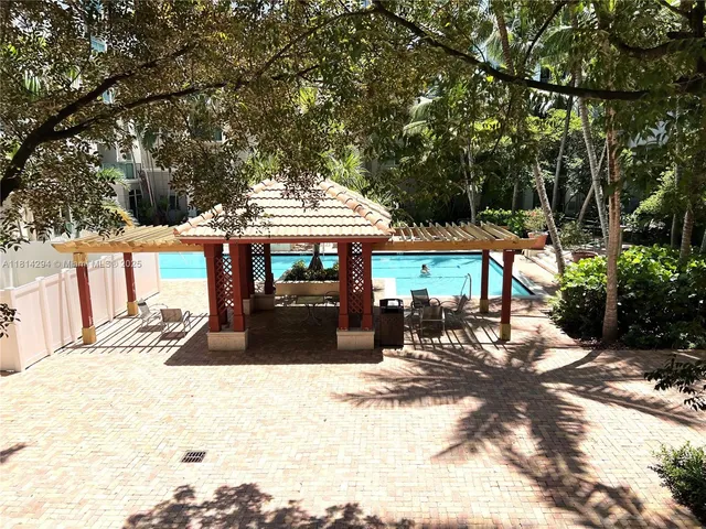 a view of a patio with a table and chairs under an umbrella with large trees