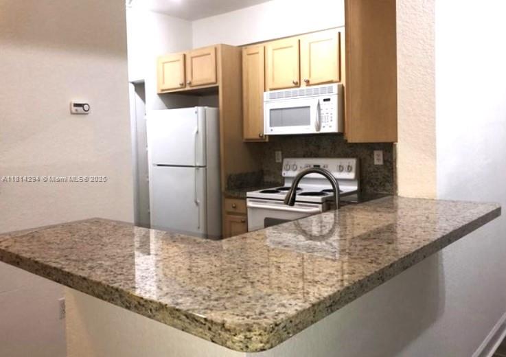 6001 Southwest 70th Street, Unit 252 South Miami, FL 33143 - Photo 9 of 15 a kitchen with granite countertop a sink a stove and a refrigerator