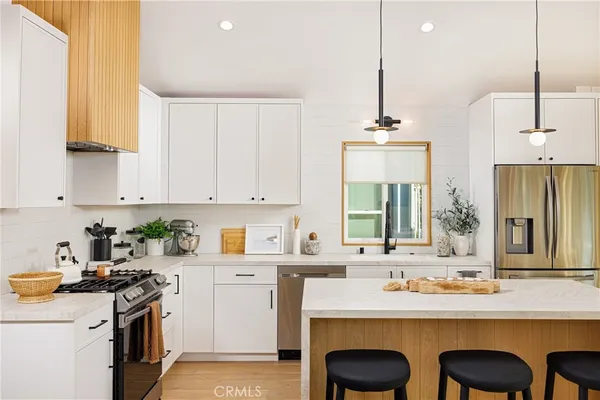 a kitchen with stainless steel appliances a sink stove and white cabinets with wooden floor
