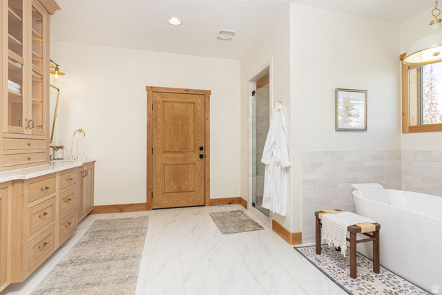 382 Ridgeview Street, Unit 8 & 9 Brian Head, UT 84719 - Photo 17 of 52 Bathroom featuring a floating double vanity with a marble-finish countertop, a freestanding soaking tub, a glass-enclosed shower, wood-finish flooring, and natural wood trim accents