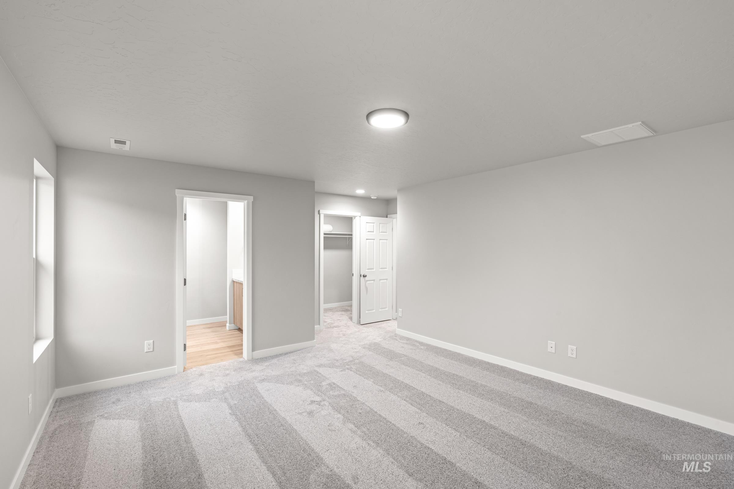 924 Northeast Trailridge Court Mountain Home, ID 83647 - Photo 16 of 21 Unfurnished bedroom with a walk in closet, ensuite bath, and light colored carpet