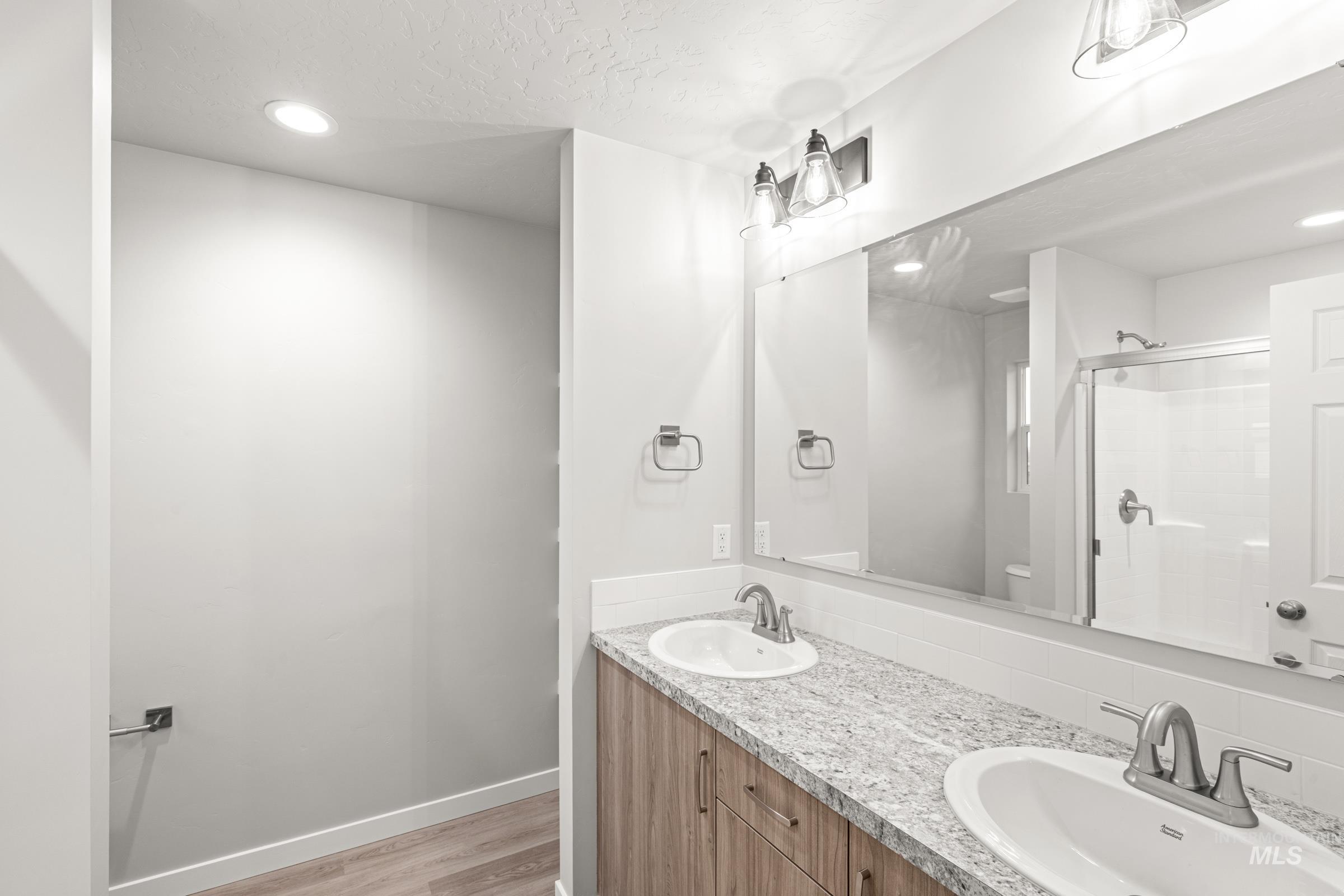 924 Northeast Trailridge Court Mountain Home, ID 83647 - Photo 19 of 21 Bathroom featuring recessed lighting, double vanity, light wood-style flooring, and a stall shower