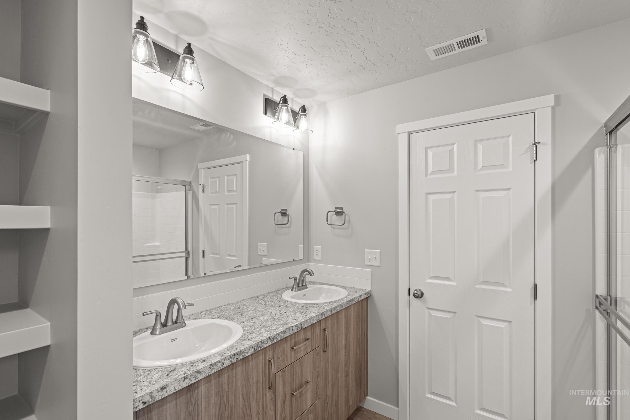 924 Northeast Trailridge Court Mountain Home, ID 83647 - Photo 20 of 21 Bathroom with double vanity, a textured ceiling, and a stall shower
