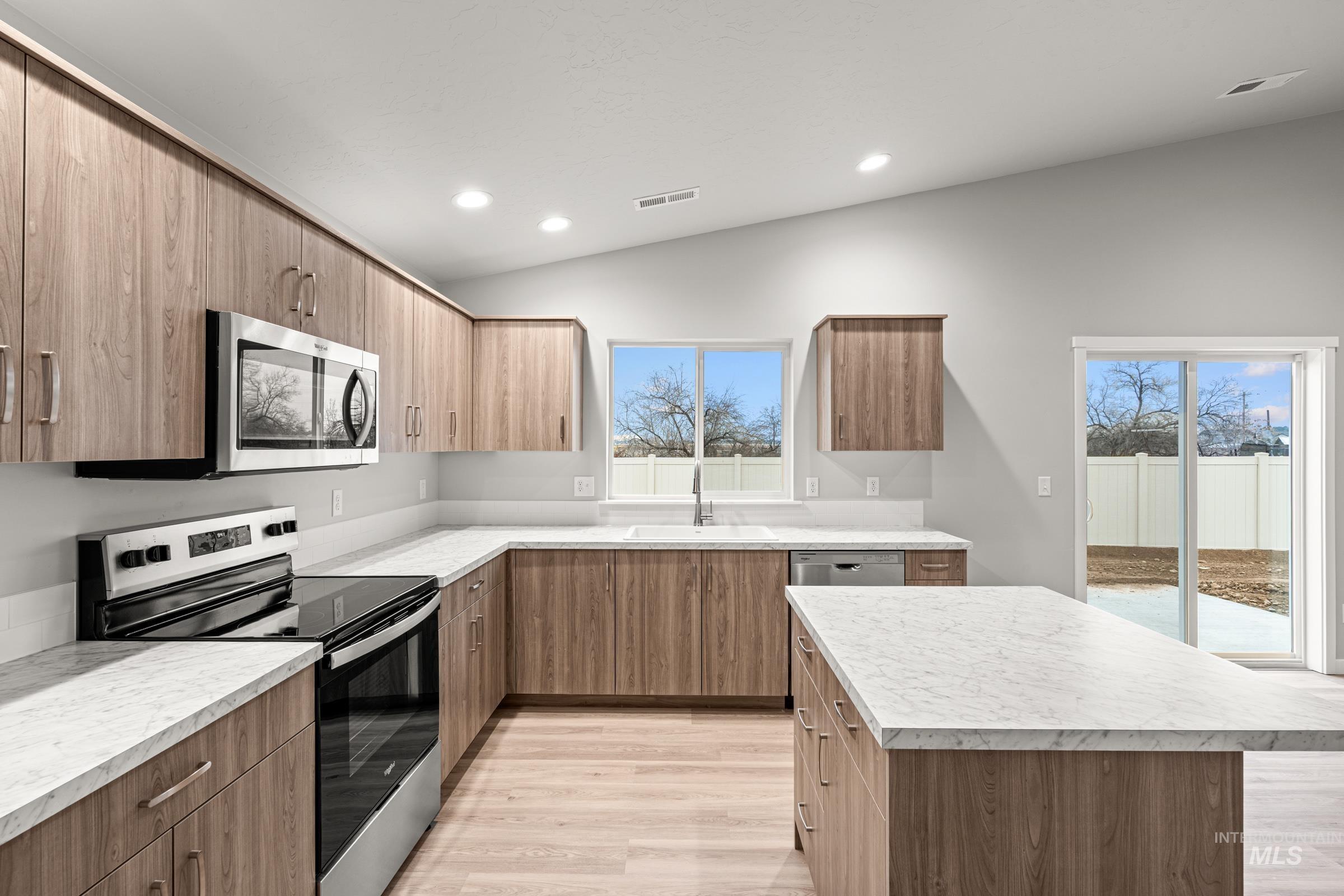 924 Northeast Trailridge Court Mountain Home, ID 83647 - Photo 5 of 21 Kitchen with stainless steel appliances, light wood finished floors, light countertops, lofted ceiling, and a kitchen island