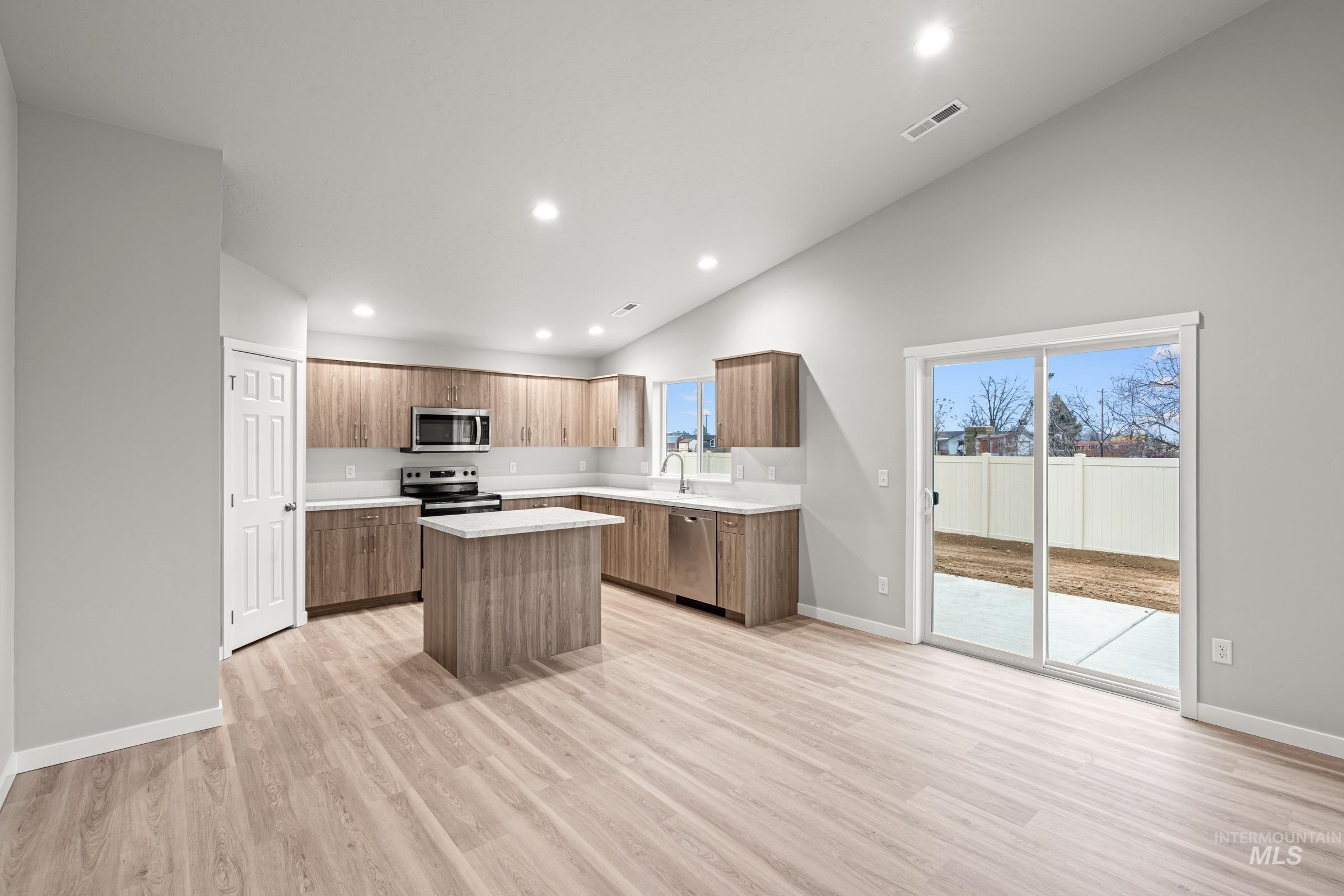 924 Northeast Trailridge Court Mountain Home, ID 83647 - Photo 6 of 21 Kitchen featuring a center island, vaulted ceiling, stainless steel appliances, wood finish cabinetry, and light wood finished floors