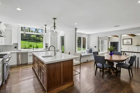 a open kitchen with stainless steel appliances granite countertop a table chairs stove a sink dishwasher and cabinets