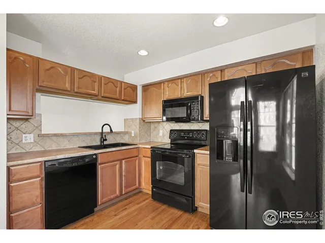 a kitchen with stainless steel appliances granite countertop a refrigerator a sink a stove and cabinets