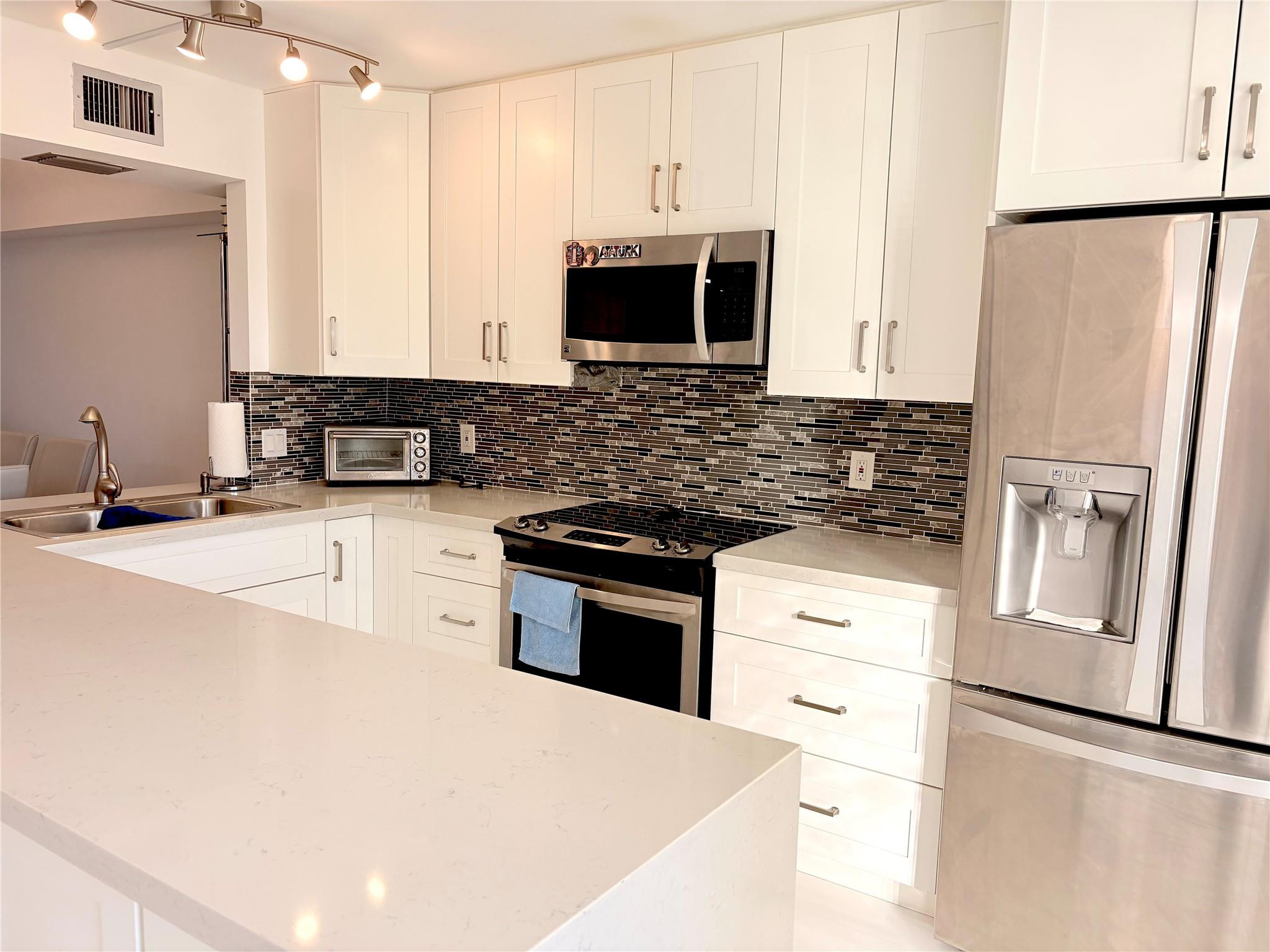 a kitchen with stainless steel appliances a refrigerator stove microwave and sink