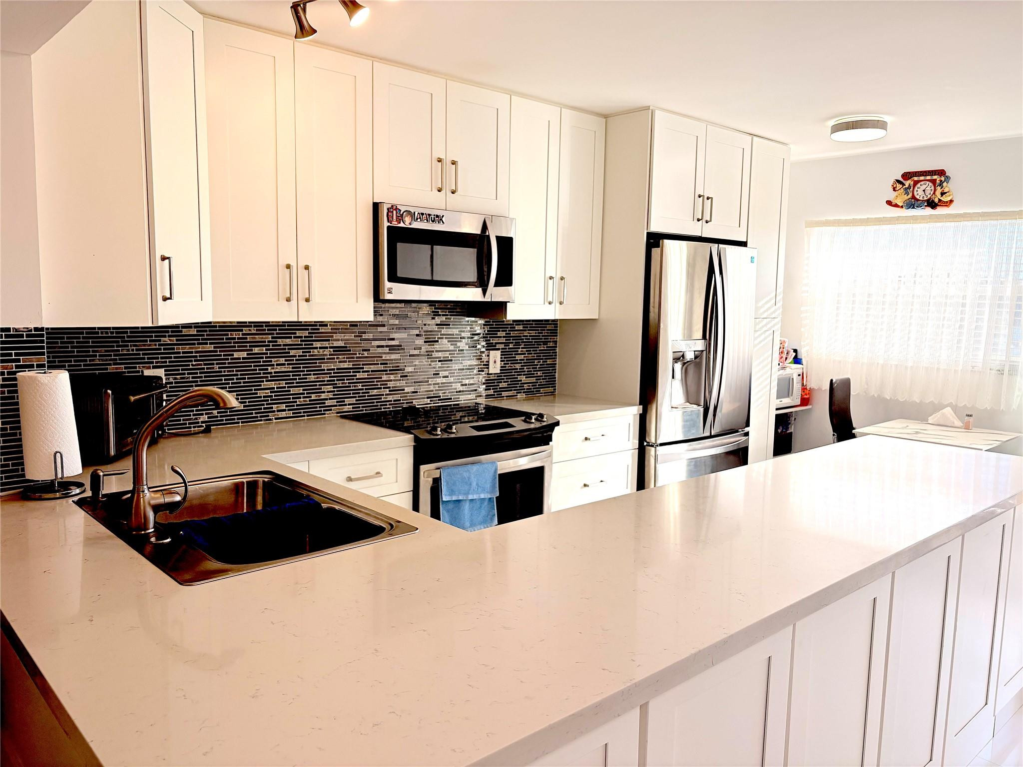 23099 Barwood Lane North, Unit 308 Boca Raton, FL 33428 - Photo 2 of 10 a kitchen with stainless steel appliances a stove a sink a refrigerator and white cabinets