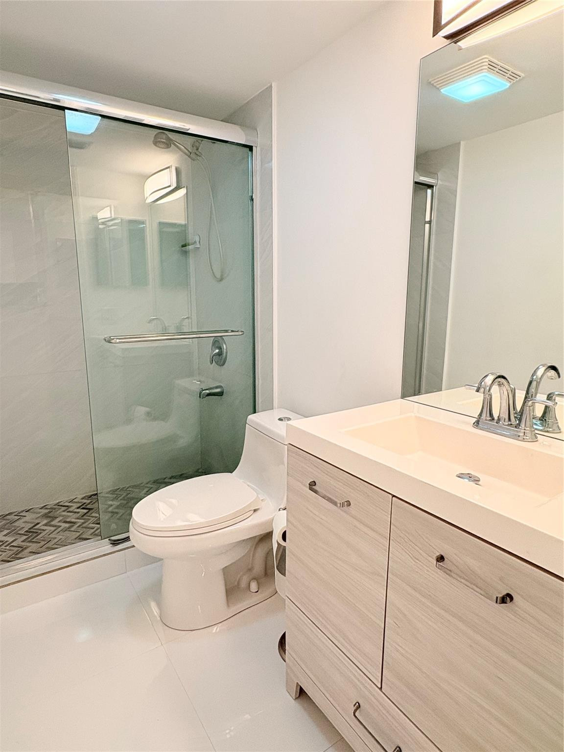23099 Barwood Lane North, Unit 308 Boca Raton, FL 33428 - Photo 10 of 10 a bathroom with a granite countertop toilet a sink and a mirror