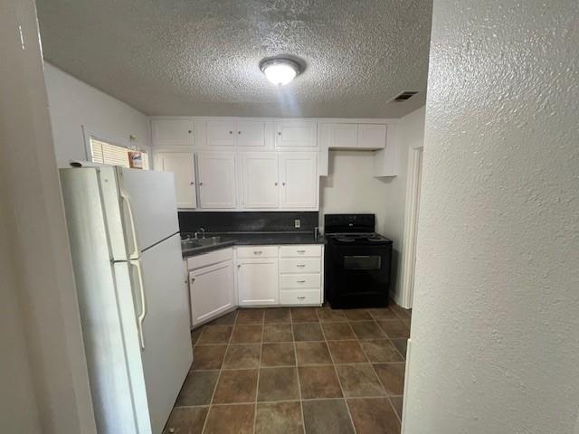 7428 Gaston Avenue Fort Worth, TX 76116 - Photo 12 of 17 a kitchen with a refrigerator and white cabinets