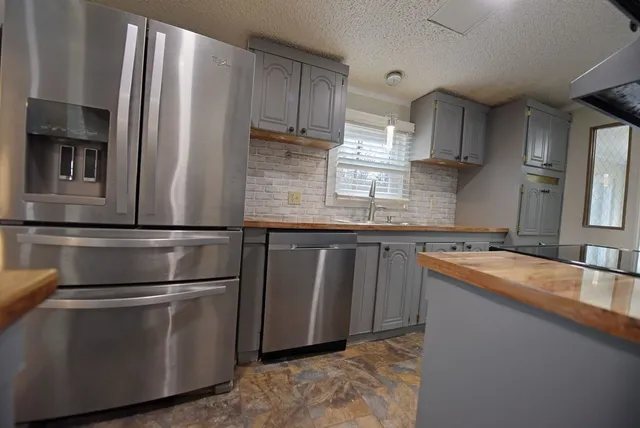 a kitchen with stainless steel appliances granite countertop a refrigerator a sink and a stove