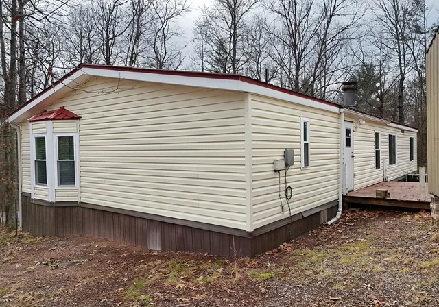 a view of a white house with a large window and wooden fence