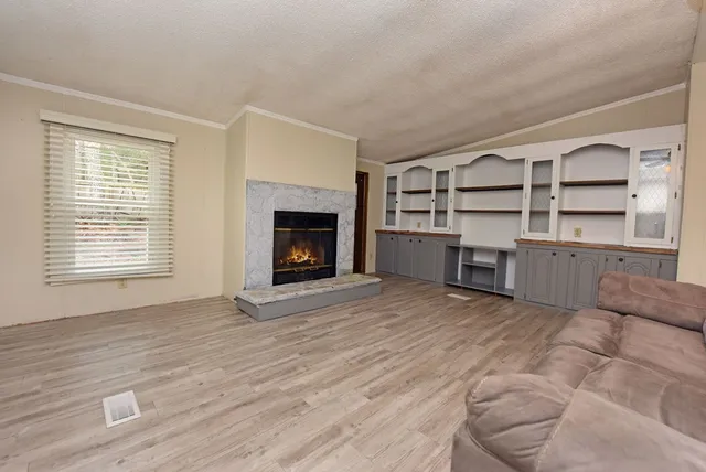 an empty room with wooden floor cabinet and fireplace