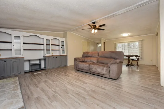 a living room with furniture kitchen view and a wooden floor