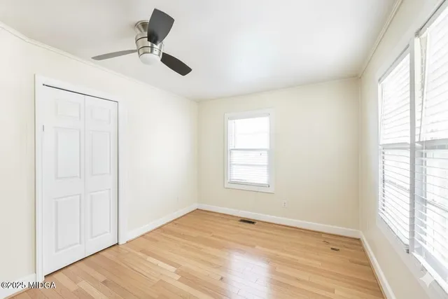 a view of an empty room with a window and wooden floor