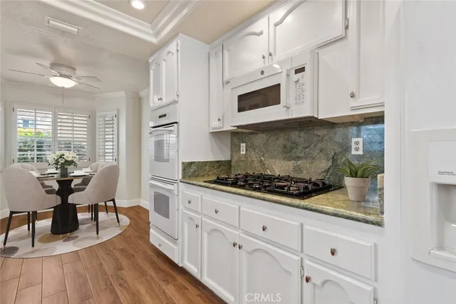 a kitchen with stainless steel appliances white cabinets and wooden floor