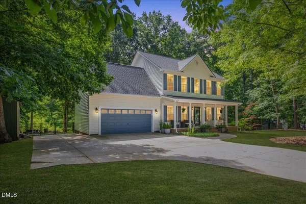 a front view of a house with a garden and trees