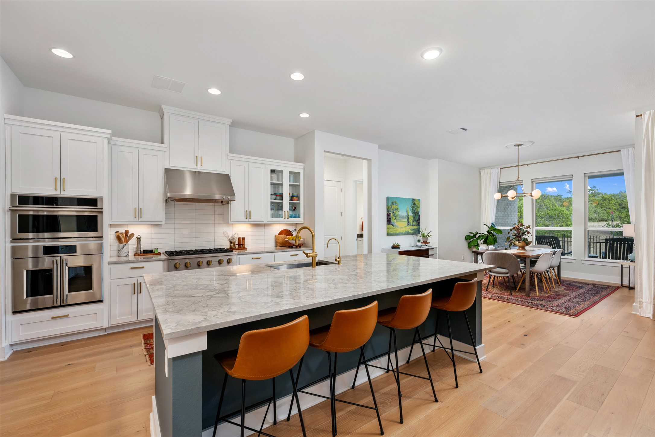 438 Pear Tree Lane Austin, TX 78737 - Photo 10 of 40 a kitchen with stainless steel appliances granite countertop a stove top oven a sink dishwasher a dining table and chairs with wooden floor