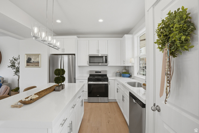 7338 South Seven Tree Lane, Unit 75 Midvale, UT 84047 - Photo 14 of 30 Kitchen featuring stainless steel appliances, white cabinets, light wood-style flooring, and light stone counters
