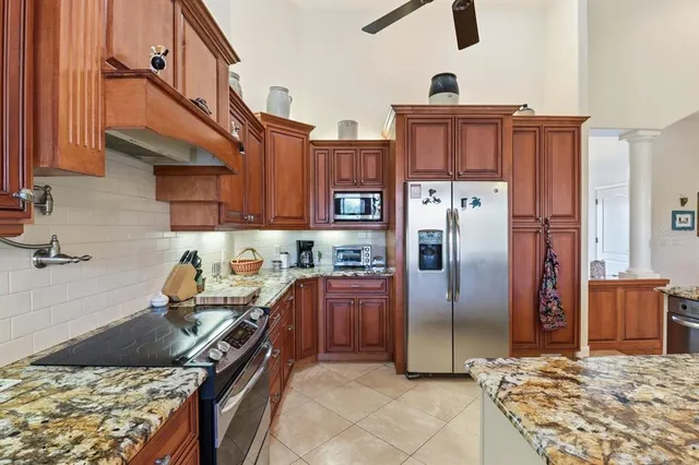 a kitchen with stainless steel appliances granite countertop a stove top oven a refrigerator and cabinets