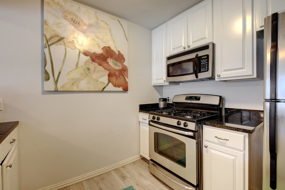 1210 Windsor Road, Unit 117 Austin, TX 78703 - Photo 5 of 17 a kitchen with stainless steel appliances white cabinets and a stove top oven