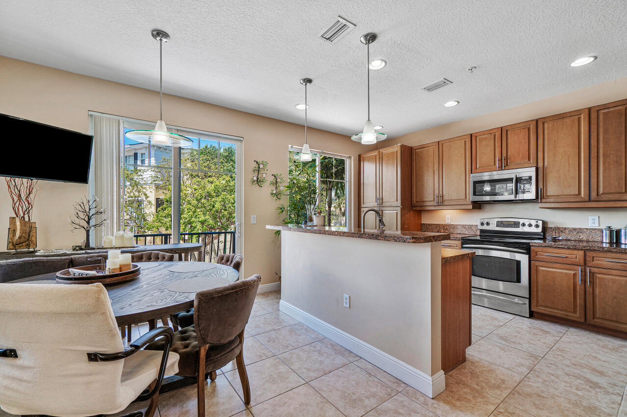 669 Northwest 38th Circle Boca Raton, FL 33431 - Photo 14 of 35 a kitchen with stainless steel appliances granite countertop a stove top oven a sink a dining table and chairs