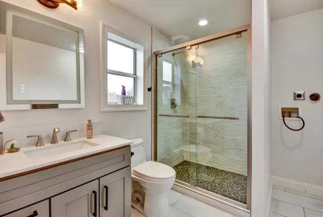 a bathroom with a shower sink vanity mirror and toilet