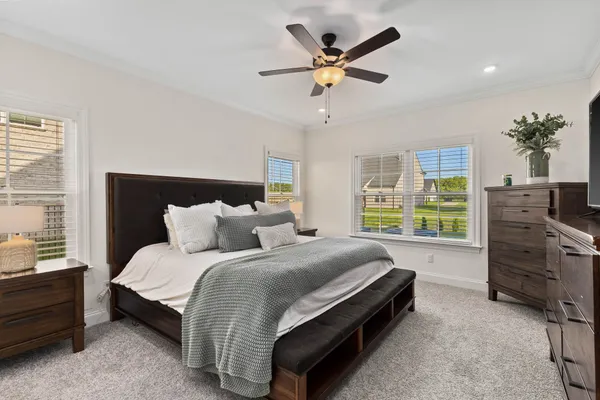 a spacious bedroom with a bed a dresser and a chandelier