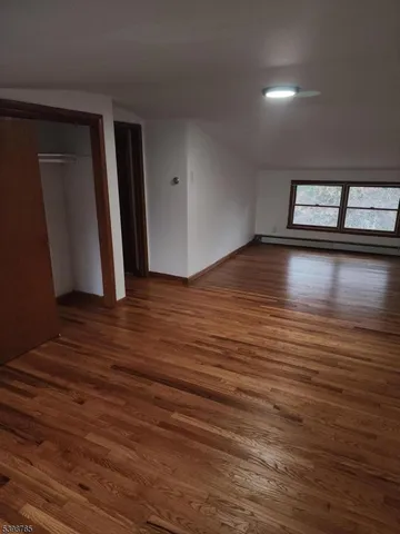 a view of empty room with window and wooden floor