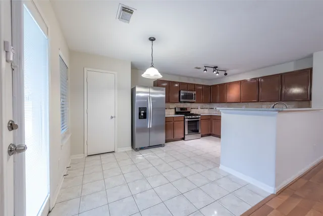 a kitchen with stainless steel appliances granite countertop a stove top oven a sink and a refrigerator