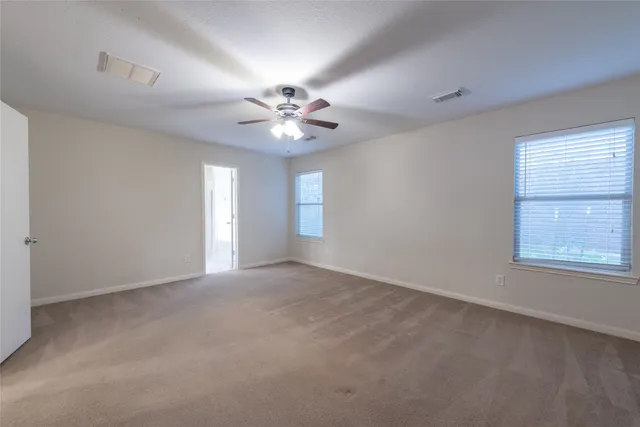 an empty room with windows and ceiling fan