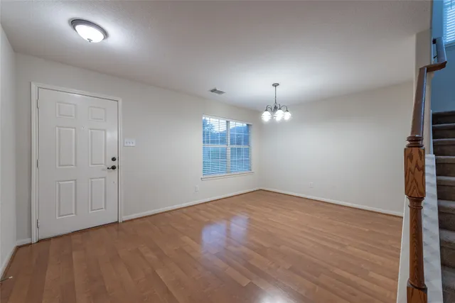 an empty room with wooden floor cabinet and windows