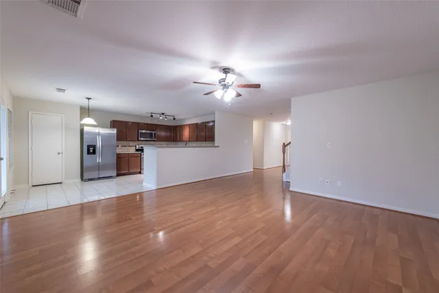 a view of a kitchen with a dishwasher a kitchen island wooden floor and a ceiling fan