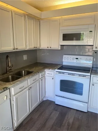 a kitchen with granite countertop white cabinets and stainless steel appliances