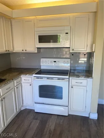 a kitchen with stainless steel appliances granite countertop a stove a microwave and a white cabinets