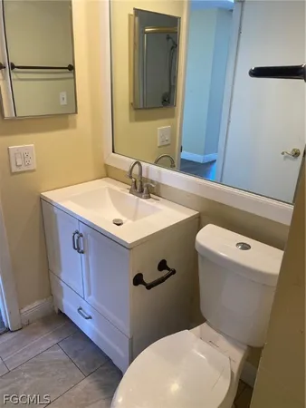 a bathroom with a granite countertop toilet sink and mirror