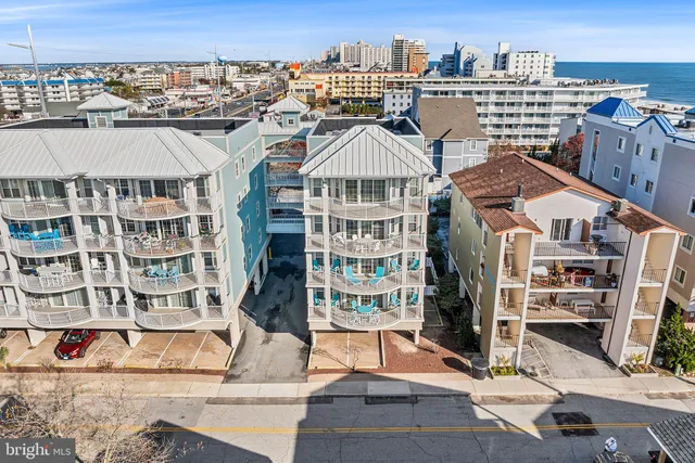 a front view of a building with lot of cars and trees