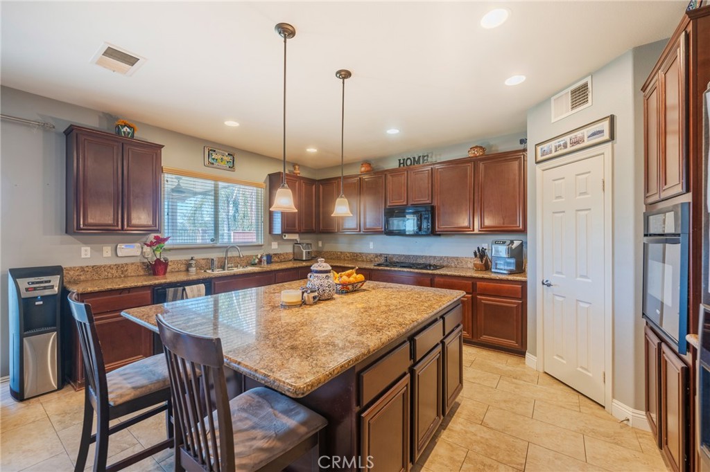 17073 Spring Canyon Place Riverside, CA 92503 - Photo 7 of 43 a kitchen with stainless steel appliances granite countertop a kitchen island a stove a table and chairs