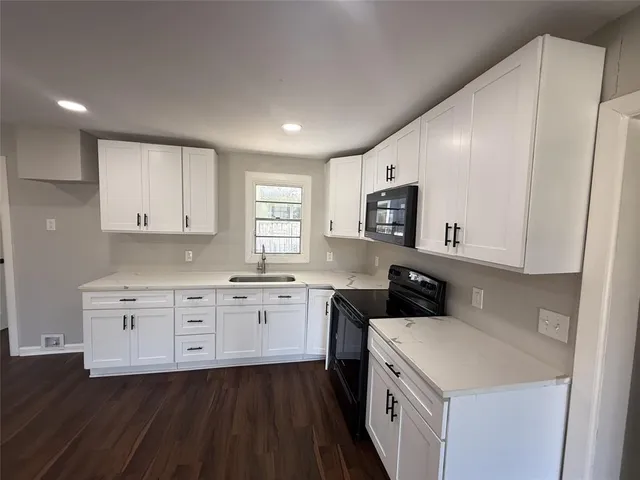 a kitchen with granite countertop white cabinets and white appliances