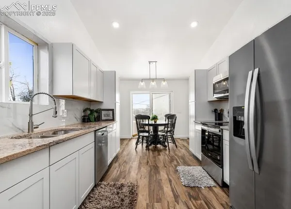 a kitchen with granite countertop a sink stove refrigerator and cabinets