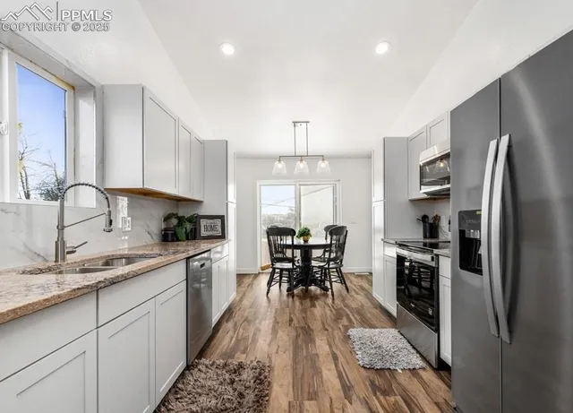 a kitchen with granite countertop a sink stove refrigerator and cabinets