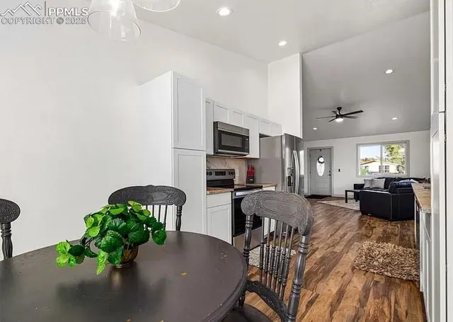 a living room with furniture potted plant and kitchen view