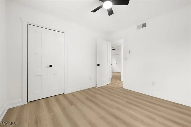 an empty room with wooden floor and ceiling fan