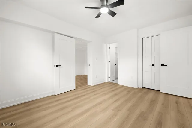 an empty room with wooden floor ceiling fan and windows