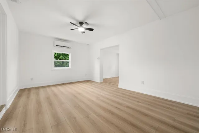 an empty room with wooden floor ceiling fan and window