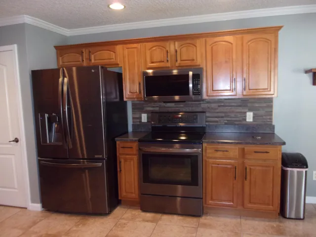 a kitchen with granite countertop a refrigerator and a stove top oven