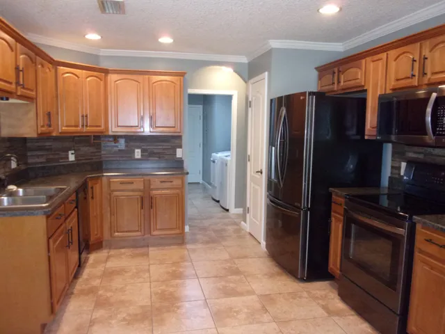 a kitchen with stainless steel appliances granite countertop a refrigerator stove and sink