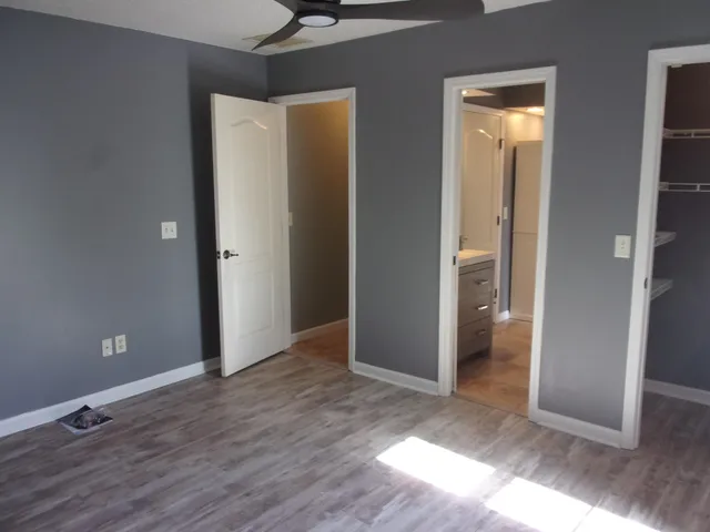 an empty room with wooden floor closet and windows